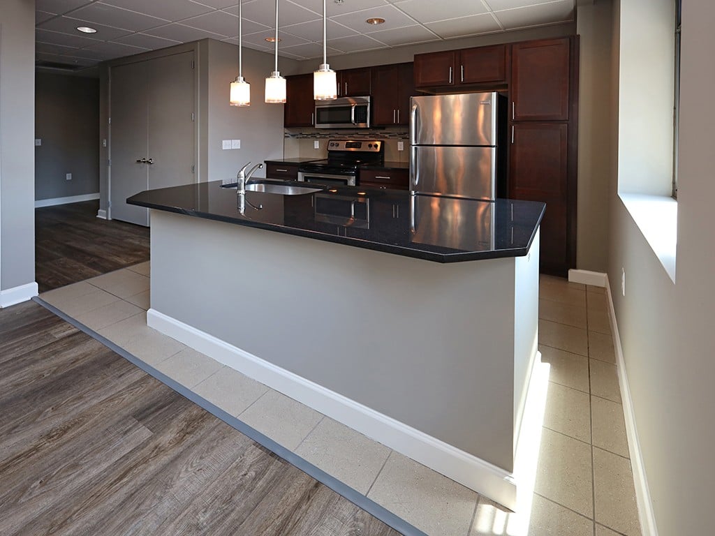 A kitchen with a black counter top and stainless steel appliances.